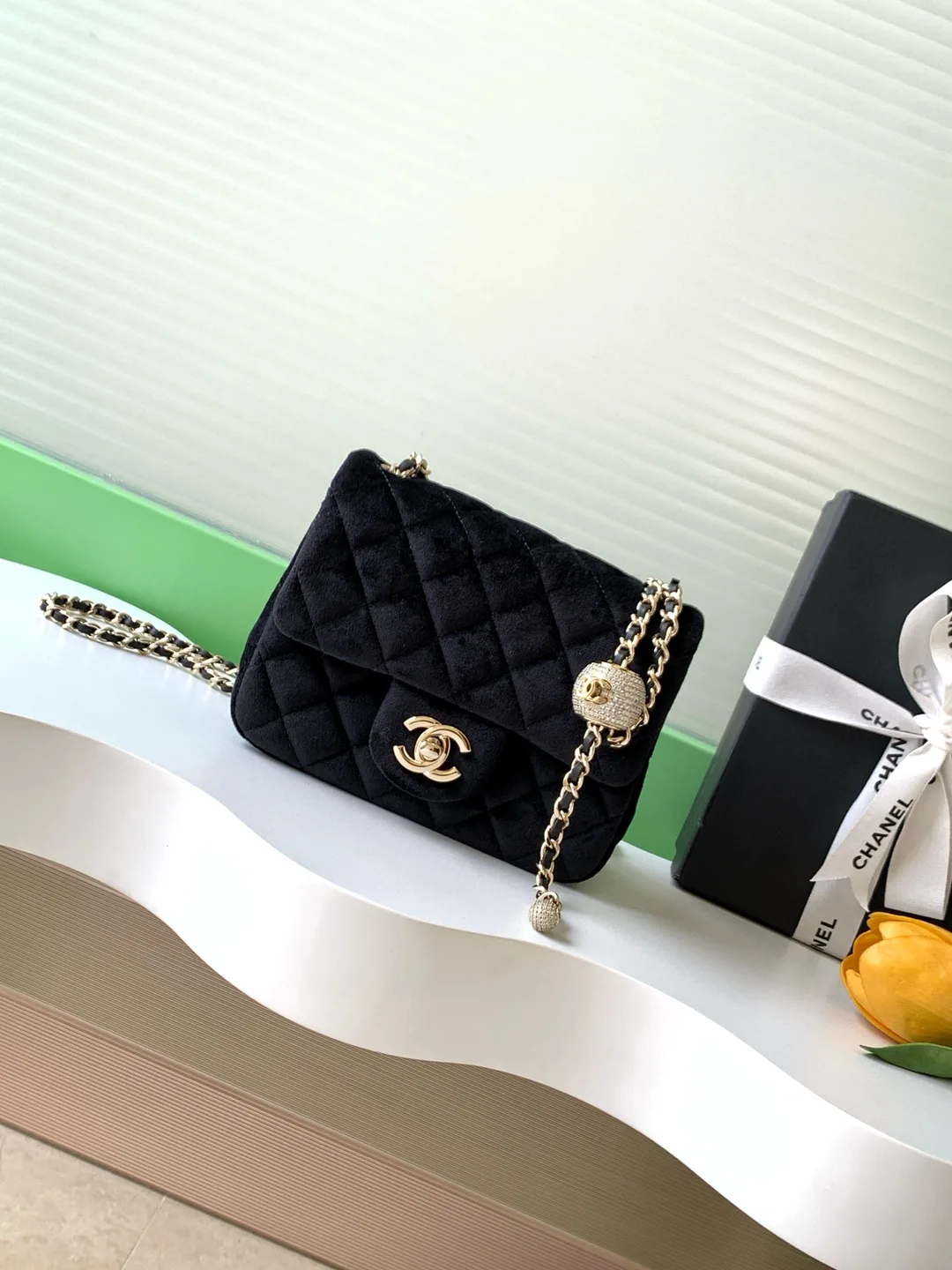 Chanel Classic Flap: geantă flap din catifea neagră matlasată, cu închidere dublu C și lanț auriu.